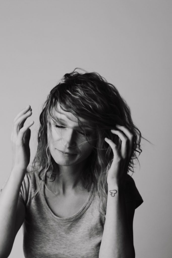 Frau mit Haaren im Gesicht und grauem Tshirt